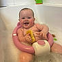 baby, bath, bathtub, bubbles, child, smiling, sitting, toy, yellow_sponge, pink_bath_seat, water, happy, cute, skin, head, arms, legs, bathroom, tile_wall, infant