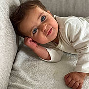 Chamss a rejoint le concours — aidez-le/la à gagner de superbes lots ! baby, blanket, blue_eyes, child, closeup, couch, cozy, curious, face, hand, head, indoor, infant, person, portrait, relaxed, skin, smile, soft_texture, white_clothing