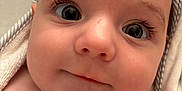 Ollie joined the competition — help win amazing prizes! baby, close_up, face, towel, skin, eyes, eyelashes, cheeks, infant, portrait, cute, soft_texture, striped, head, newborn, expression, child, human, wrapped, smile