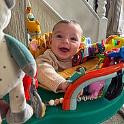Ollie joined the competition — help win amazing prizes! baby, smiling, child, toys, activity_center, indoor, happy, face, clothing, home, carpet, furniture, play, colorful, cute, person, sweater, expression, infant, seat