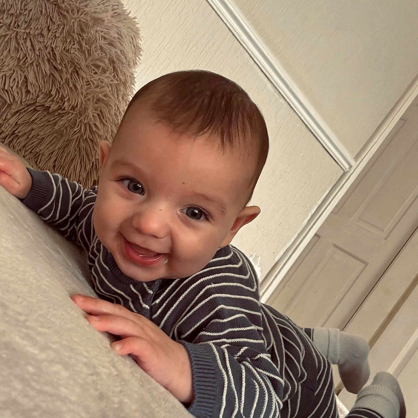 Ollie joined the competition — help win amazing prizes! baby, candid, child, cozy, cute, door, face, feet, floor, hands, happy, indoor, infant, lying_down, person, pillow, smiling, striped_clothing, toddler, wall