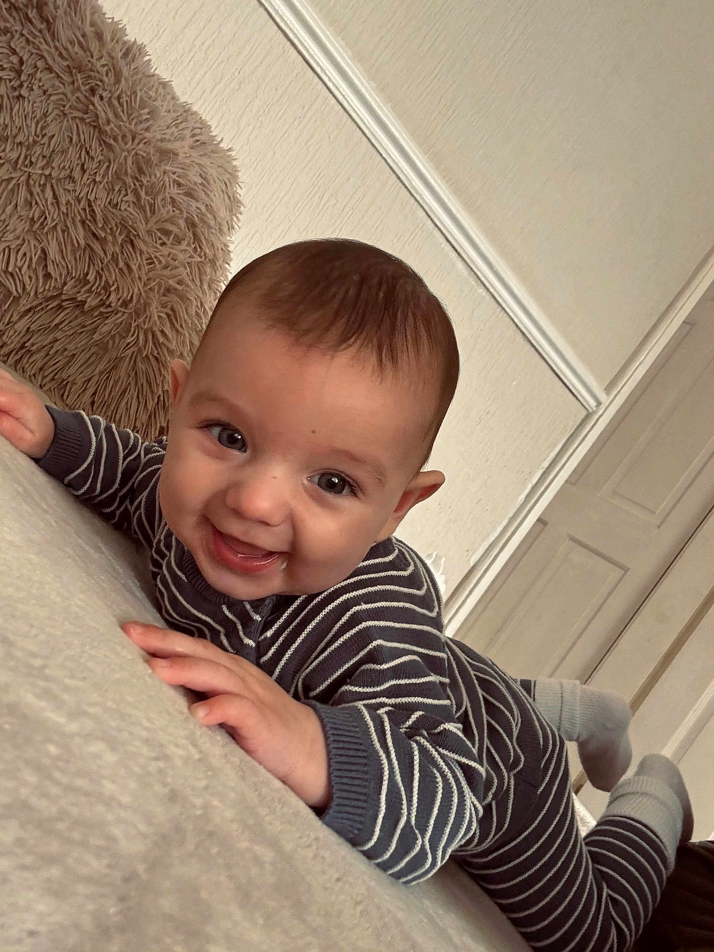 Ollie joined the competition — help win amazing prizes! baby, smiling, striped_clothing, infant, lying_down, indoor, pillow, happy, person, toddler, face, hands, feet, cozy, wall, door, floor, candid, child, cute