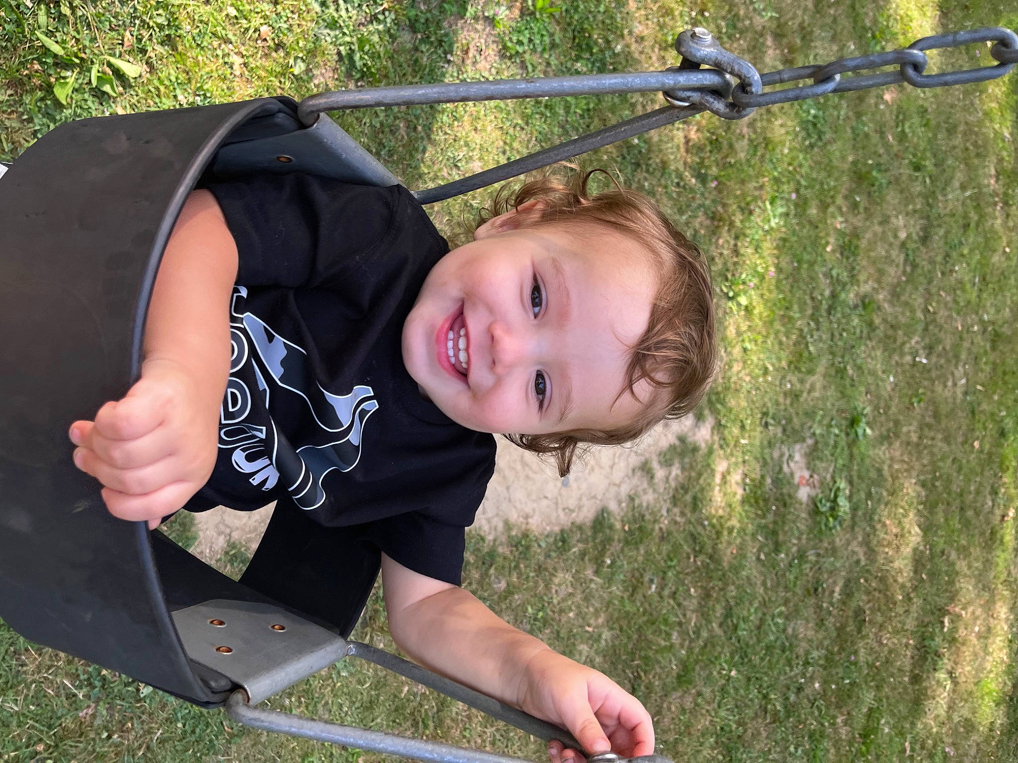 Jody is registered to the contest to win money with this photo: child, facial_expression, fun, grass, grass_family, grassland, happy, joy, lawn, leisure, outdoor_play_equipment, people_in_nature, person, plant, public_space, recreation, smile, summer, swing, t_shirt