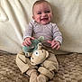baby, beige_pants, blanket, casual_clothing, child, cozy, cute, drool, happy, indoor, infant, person, plush_toy, portrait, seated, smiling, socks, soft_toy, striped_shirt, texture