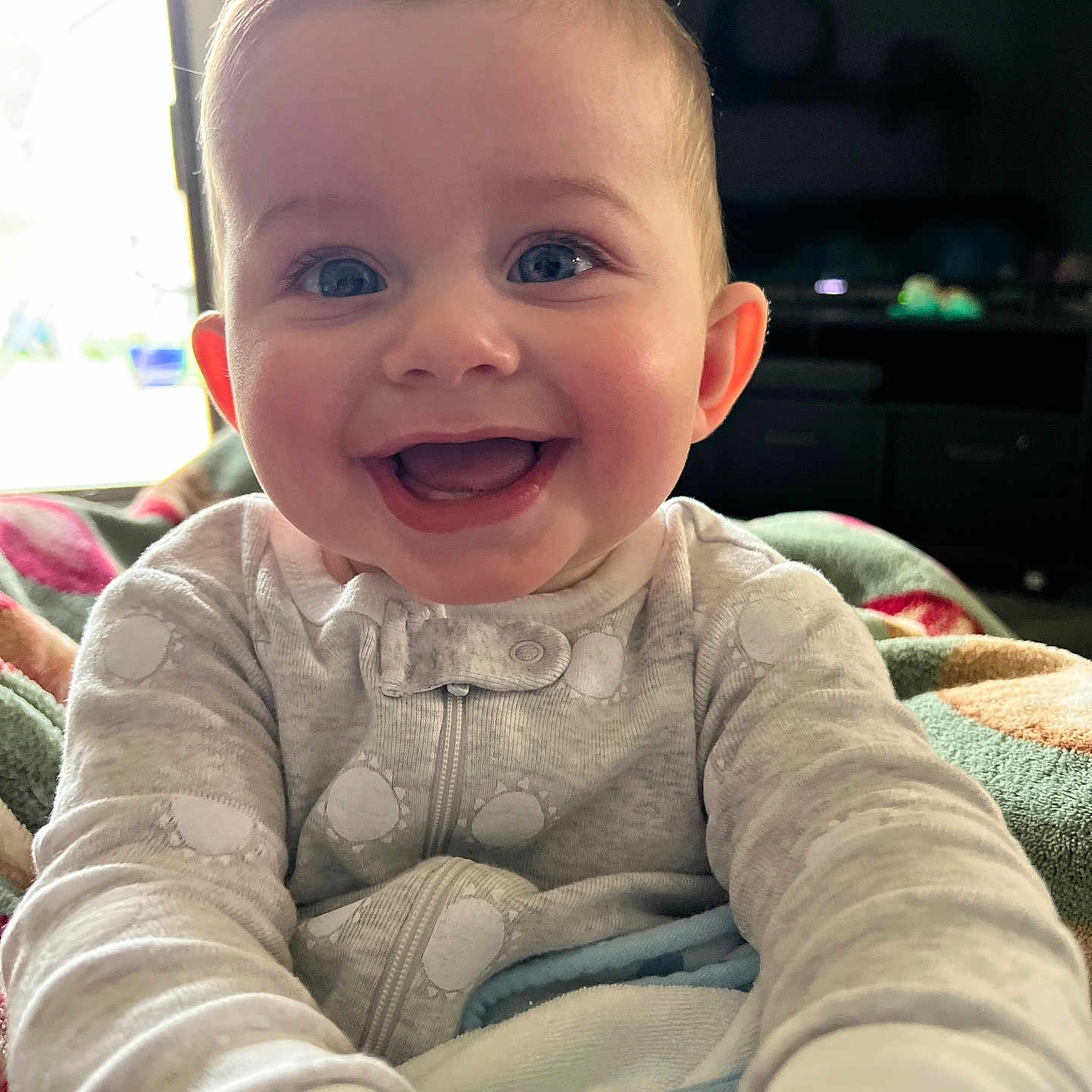 Oliver is registered to the contest to win money with this photo: baby, blanket, blue_eyes, child, cozy, cute, expression, face, happy, home, indoor, infant, pajamas, person, portrait, reaching, smiling, soft_light, warm, young_child