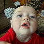 baby, child, face, drool, red_shirt, living_room, couch, blanket, christmas_tree, holiday_decor, carpet, furniture, indoor, person, blur, head, expression, home, infant, closeup