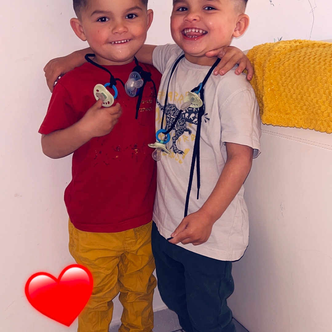 Kayden Aaron a rejoint le concours — aidez-le/la à gagner de superbes lots ! child, boys, hug, smile, pacifier, indoor, sneakers, red_shirt, yellow_pants, white_shirt, dark_pants, tile_floor, wall, shelf, yellow_towel, heart_emoji, happy, friendship, cute, portrait