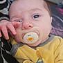 baby, pacifier, yellow_outfit, close_up, infant, hand, face, eyes, skin, comfort, soft, indoor, person, child, resting, cute, young, portrait, expression, clothing