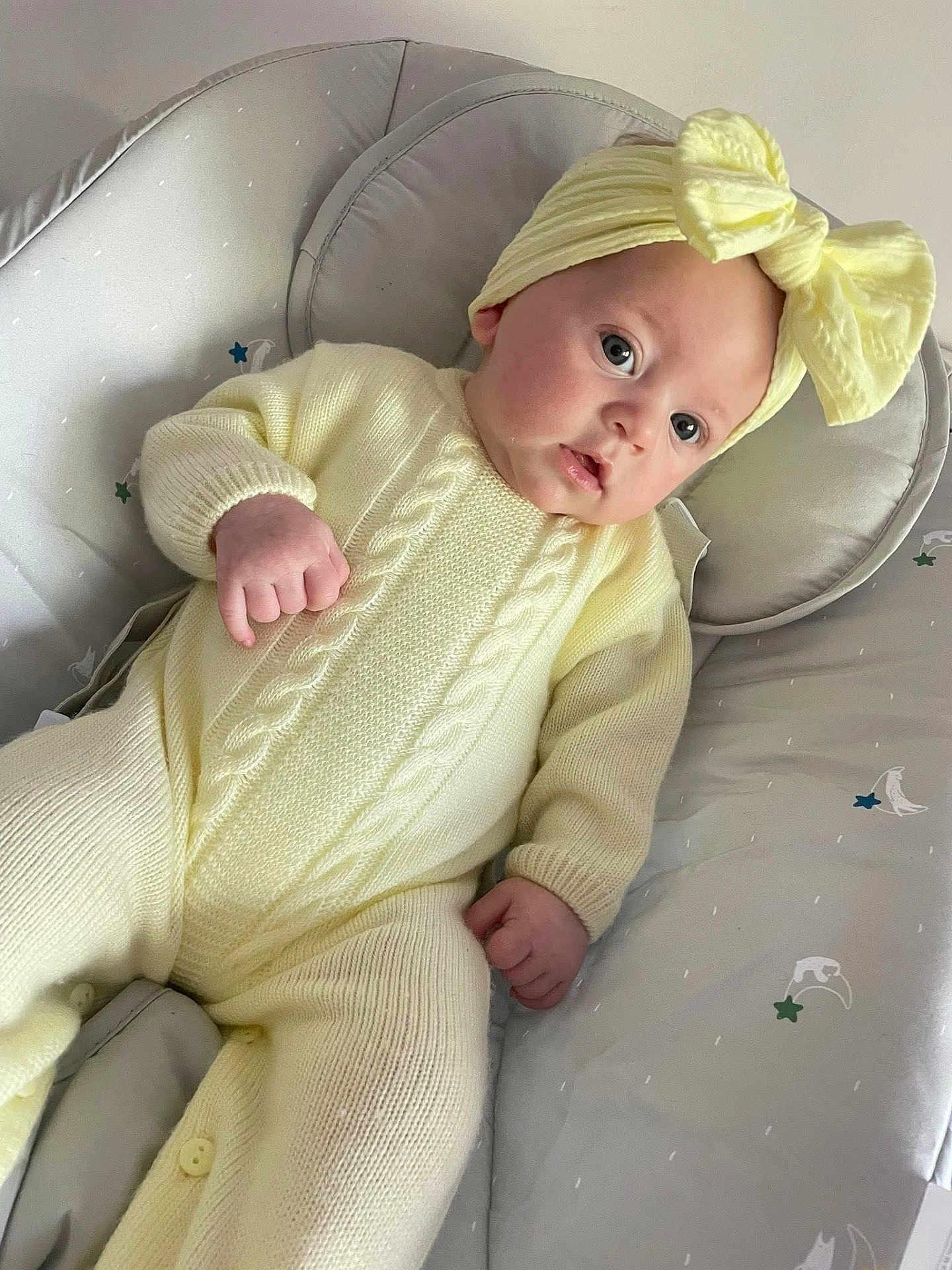 Marnie-Maria joined the competition — help win amazing prizes! baby, infant, yellow_clothing, headband, bow, knitwear, baby_seat, moons, stars, soft_furniture, cute, portrait, child, indoors, cozy, hands, face, expression, lying_down, curious