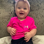 Marnie-Maria joined the competition — help win amazing prizes! baby, child, smiling, pink_shirt, headband, bow, couch, blanket, happy, infant, person, indoors, cute, chubby_cheeks, shorts, seated, plush, bright_colors, portrait, clothing