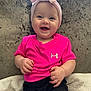 baby, child, smiling, pink_shirt, headband, bow, couch, blanket, happy, infant, person, indoors, cute, chubby_cheeks, shorts, seated, plush, bright_colors, portrait, clothing