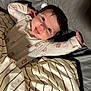 baby, child, face, smile, eyes, blanket, striped_blanket, clothing, onesie, bed, pillow, happy, infant, lying_down, cute, indoors, person, skin, hair, stretching