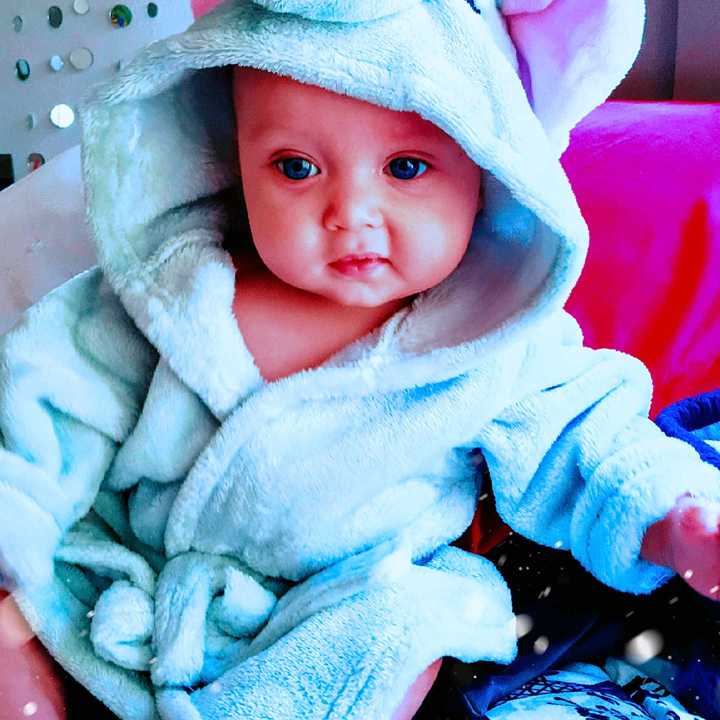 O'Ryen joined the competition — help win amazing prizes! baby, child, blue_robe, hood, elephant_costume, cute, indoor, plush, face, big_eyes, chubby_cheeks, pink_cushion, decor, soft_texture, sitting, person, infant, portrait, warm_clothing, curious_expression