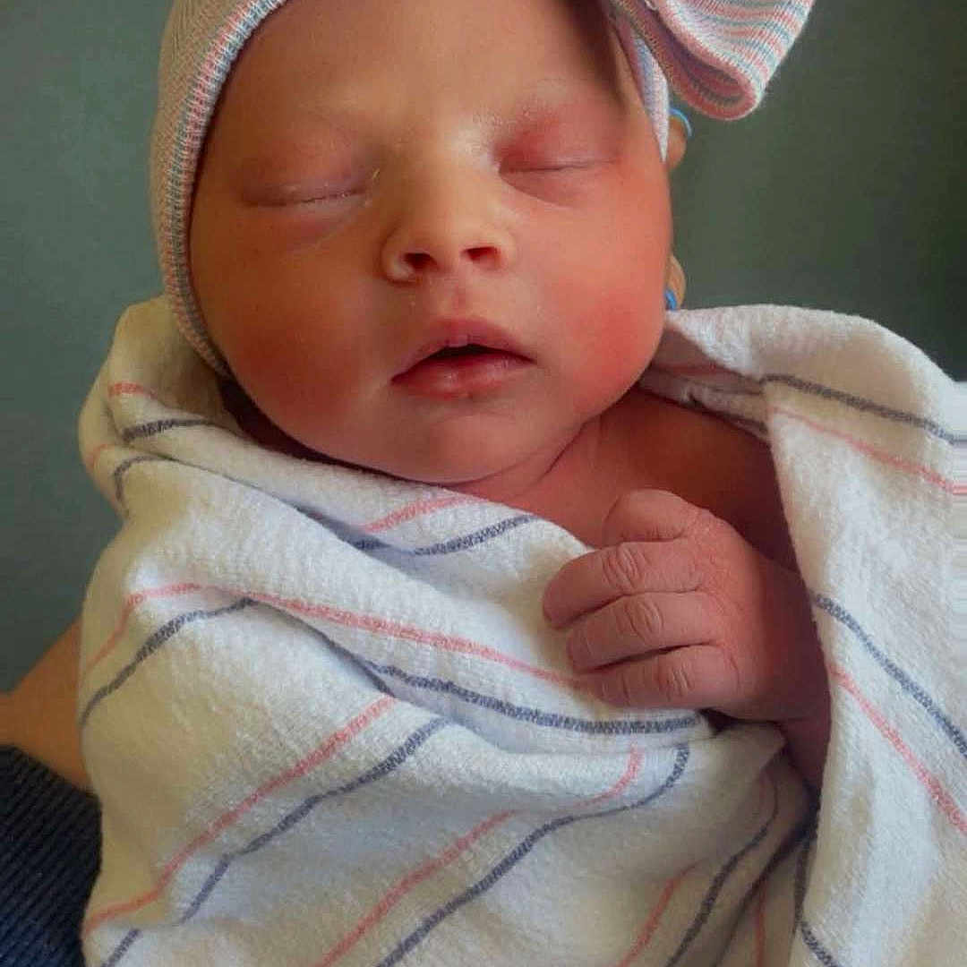 Lila is registered to the contest to win money with this photo: newborn, baby, sleeping, hat, bow, blanket, striped, wrapped, cozy, infant, child, person, hand, cute, peaceful, resting, indoors, soft, portrait, hospital