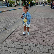 Isaac participe au concours pour gagner de l'argent avec cette photo : bench, casual_clothing, child, daytime, greenery, jacket, lamp_post, outdoor, palm_tree, park, pavement, people, shorts, sidewalk, sky, toddler, tree, urban, walking, yellow_pouch