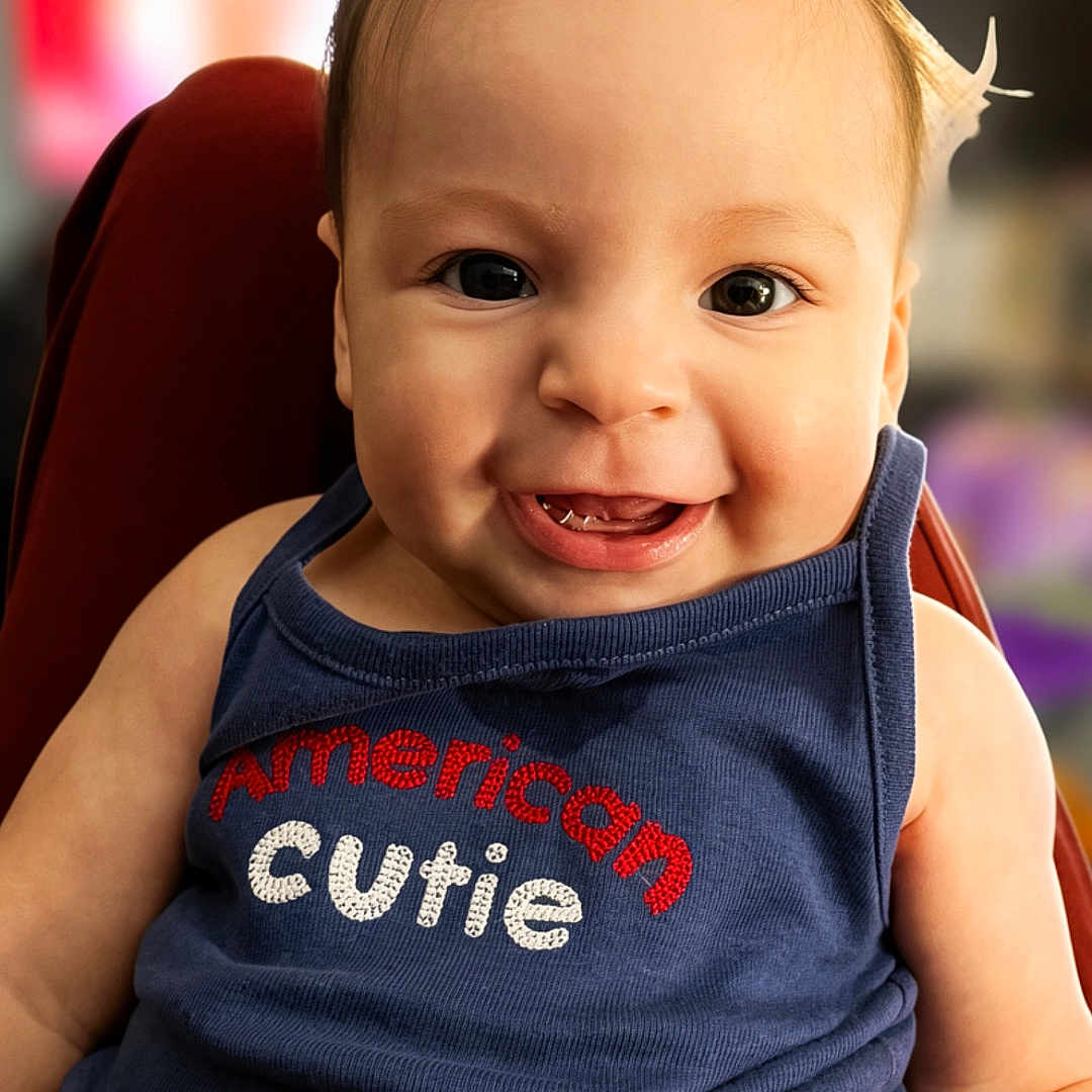Eleia joined the competition — help win amazing prizes! baby, child, smiling, face, tank_top, hair_ponytail, clothing, blue, cute, portrait, sitting, infant, happy, person, indoor, closeup, young_child, expression, eyes, skin