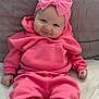 baby, infant, pink_clothing, headband, bow, hoodie, pants, sitting, cute, smiling, pillow, soft_fabric, indoors, child, portrait, young_child, cozy, person, sock, comfortable