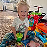 toddler, child, smiling, indoors, carpet, toy, book, cup, playtime, kitchen, colorful, casual_clothing, blond_hair, happy, floor, young_child, reading, plastic_toys, sitting, household