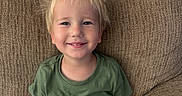 Mark joined the competition — help win amazing prizes! child, smile, blond_hair, green_shirt, dinosaur_print, sippy_cup, couch, brown_couch, indoor, happy, casual, toddler, portrait, seated, young_child, comfortable, home, relaxed, person, cute