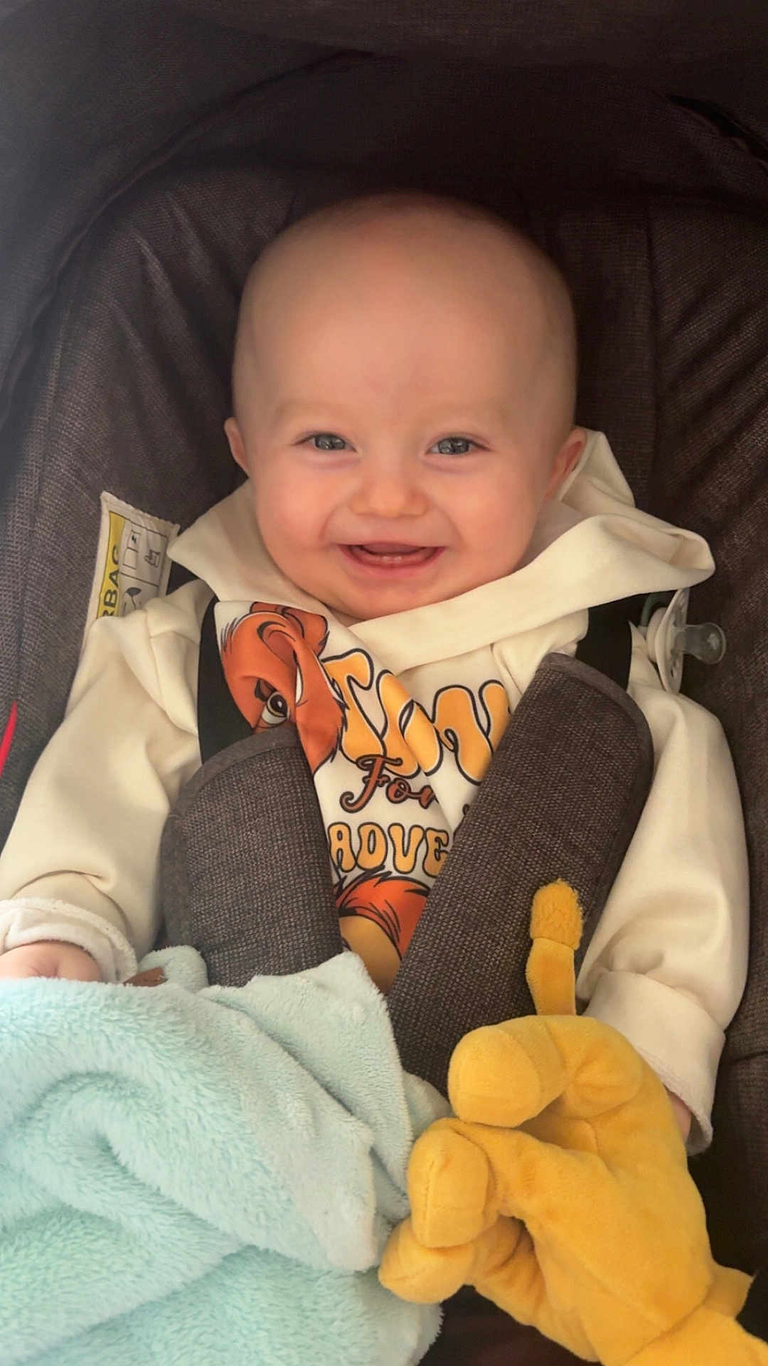 Jonathane a rejoint le concours — aidez-le/la à gagner de superbes lots ! baby, blanket, blue, car_seat, child, clothing, comfort, cute, face, happy, hoodie, indoor, infant, person, plush_toy, portrait, seatbelt, smiling, soft, yellow