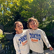 Imran a rejoint le concours — aidez-le/la à gagner de superbes lots ! baseball, boys, casual_wear, child, curly_hair, friends, greenery, happy, hugging, matching_clothes, nature, outdoor, pond, rocks, siblings, smiling, sunlight, sweatshirt, trees, wooden_deck