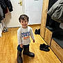 boots, boy, cabinet, casual, child, clothing, door, floor, funny, happy, indoor, jacket, oversized, person, room, shoes, smiling, standing, wooden_floor, young