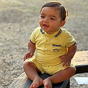Zayd participe au concours pour gagner de l'argent avec cette photo : baby, child, yellow_outfit, sitting, bench, outdoor, natural_light, happy, curious, portrait, head, face, feet, wood, sunlight, smile, infant, young_child, casual_clothing, nature