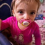 toddler, pacifier, pink_shirt, child, indoor, close_up, curious, baby, face, eyes, toy, blanket, play_area, soft_toys, furniture, person, infant, cute, young_child, home