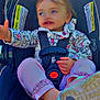 Addison is registered to the contest to win money with this photo: toddler, child, car_seat, jacket, elephant_pattern, pink_pants, pink_shoes, footwear, straps, seatbelt, smiling, reaching_hand, cute, happy, baby, outdoor, daylight, portrait, person, clothing