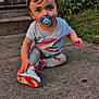Addison is registered to the contest to win money with this photo: toddler, child, pacifier, shoe, concrete, outdoor, grass, plant, curious, sitting, colorful_clothing, small_bow, red_sole, sidewalk, window, house, daylight, cute, young_child, nature