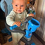 Nino participe au concours pour gagner de l'argent avec cette photo : toddler, child, tricycle, blue, indoor, toy, handlebars, floor, tile, clothing, smile, face, person, hair, footwear, seat, play, baby, transportation, curious