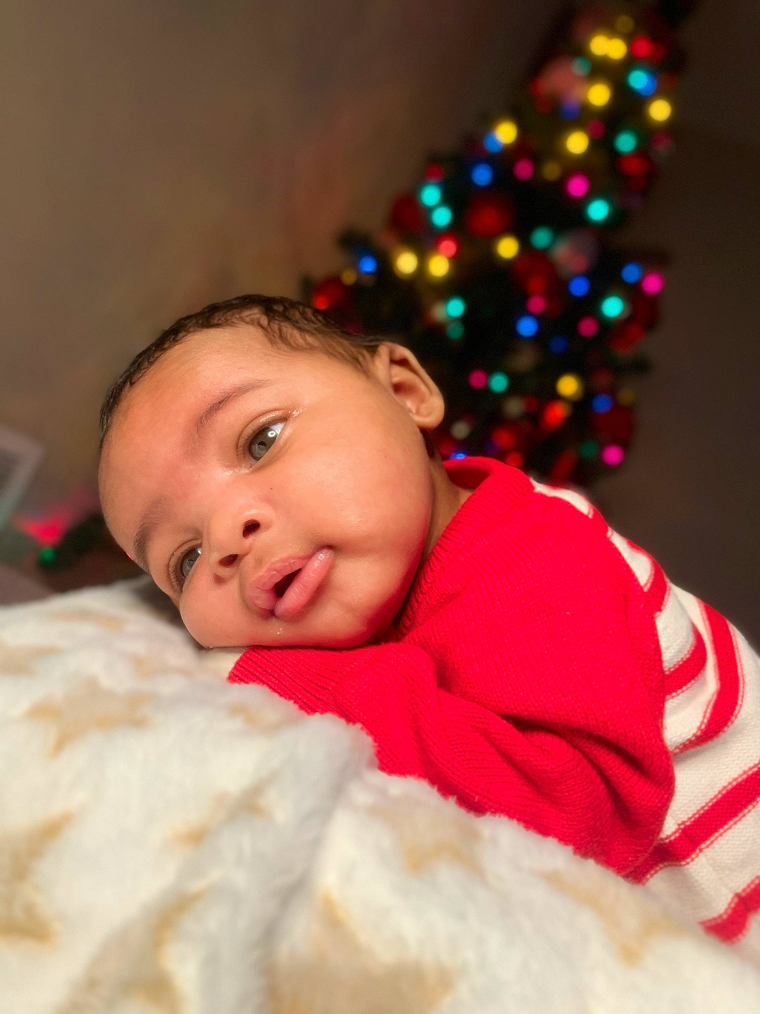 Jacob is registered to the contest to win money with this photo: baby, baby_toddler_clothing, carmine, cheek, child, christmas, christmas_decoration, christmas_tree, comfort, event, face, fun, fur, happy, head, holiday, linens, person, sitting, sleeve