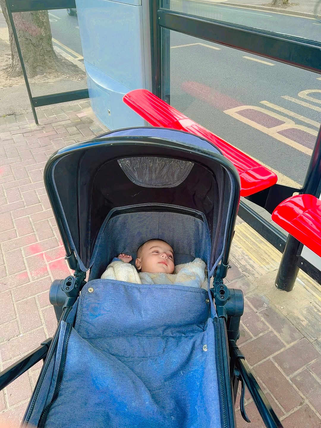 Muhammad joined the competition — help win amazing prizes! baby, stroller, infant, blue, blanket, bus_stop, bench, red, sidewalk, street, urban, outdoor, child, peaceful, waiting, transportation, pavement, canopy, daytime, casual