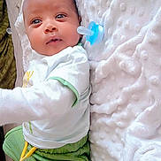 Ibrahim participe au concours pour gagner de l'argent avec cette photo : baby, infant, child, pacifier, blanket, white_blanket, green_shorts, white_shirt, lying_down, indoors, soft_texture, cute, small_person, sleepwear, socks, infant_clothing, portrait, baby_boy, young_child, resting