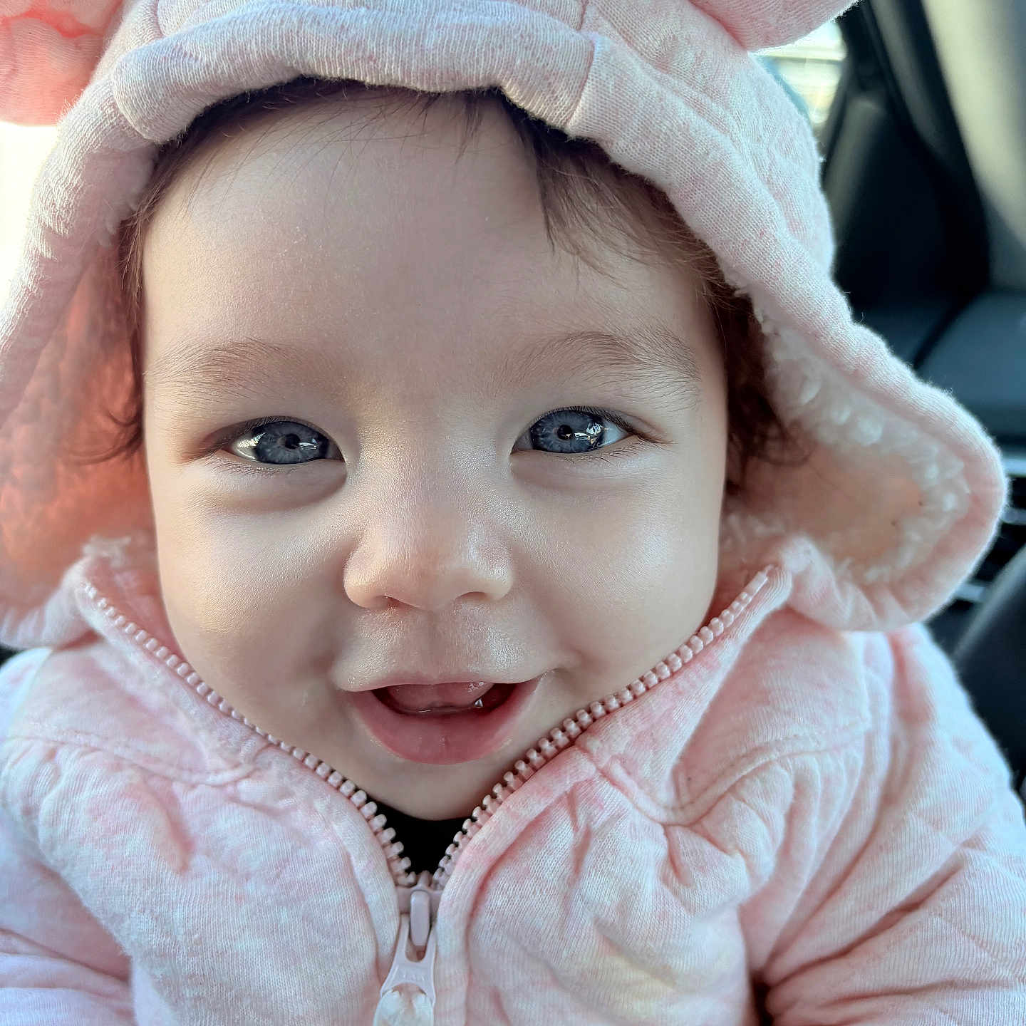 Rei joined the competition — help win amazing prizes! baby, baby_clothes, blue_eyes, car_interior, child, close_up, cozy, cute, face, happy, hood, hoodie, infant, joyful, pink_clothing, portrait, smile, warm_clothing, wearing, young_child