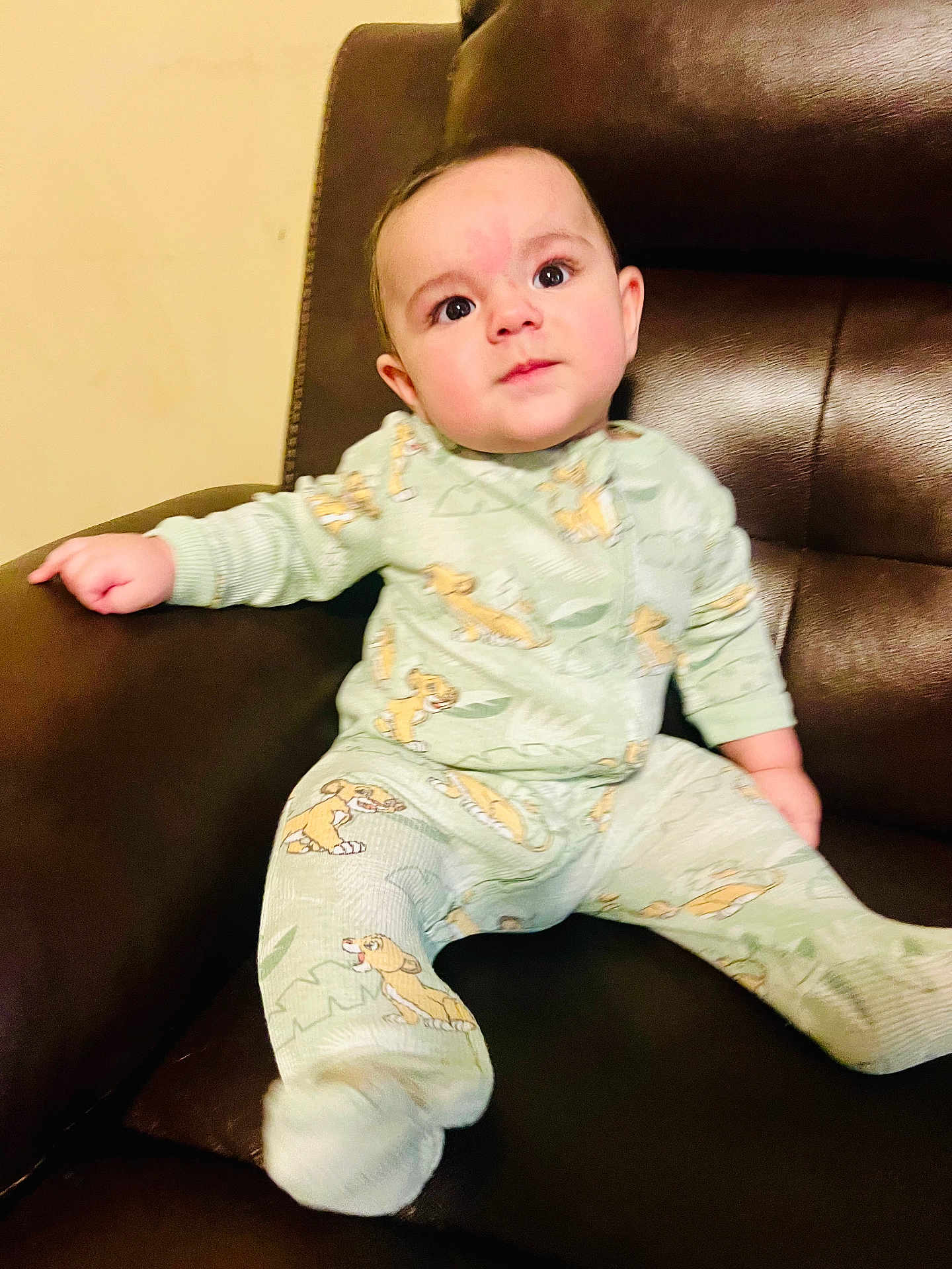 Dylan joined the competition — help win amazing prizes! baby, child, pajamas, cartoon_pattern, sitting, chair, leather, indoor, cute, infant, young_child, clothing, face, portrait, relaxing, home, furniture, cozy, curious, smiling