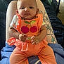 baby, child, infant, orange_clothing, sitting, tattoo, person, legs, blanket, home_interior, toy, floor, cute, face, hands, casual, relaxed, indoor, people, comfort