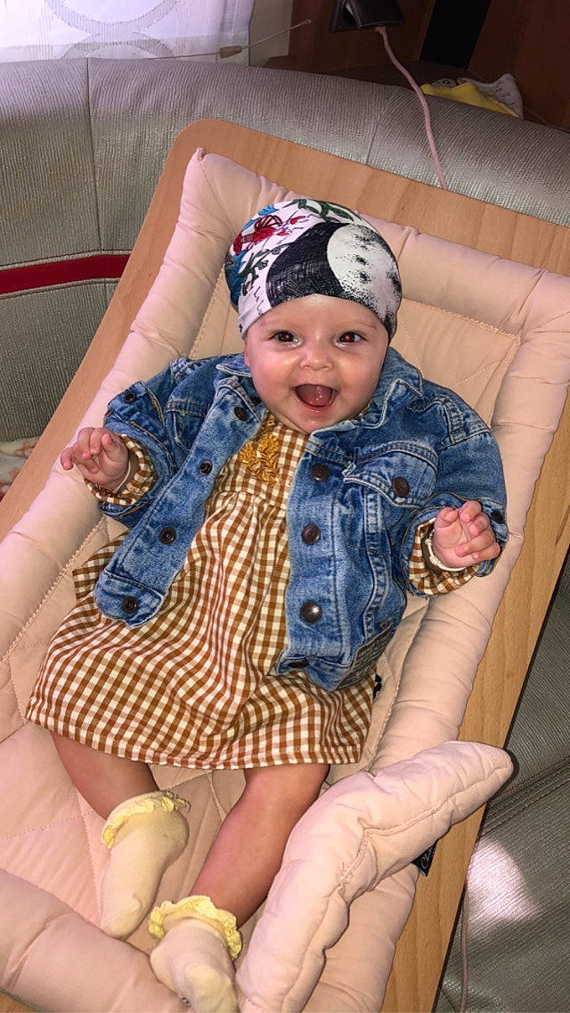 Masha participe au concours pour gagner de l'argent avec cette photo : baby, baby_toddler_clothing, cap, cheek, child, comfort, eye, fashion_accessory, fun, happy, headwear, lap, leisure, pattern, person, purple, sitting, sleeve, smile, textile