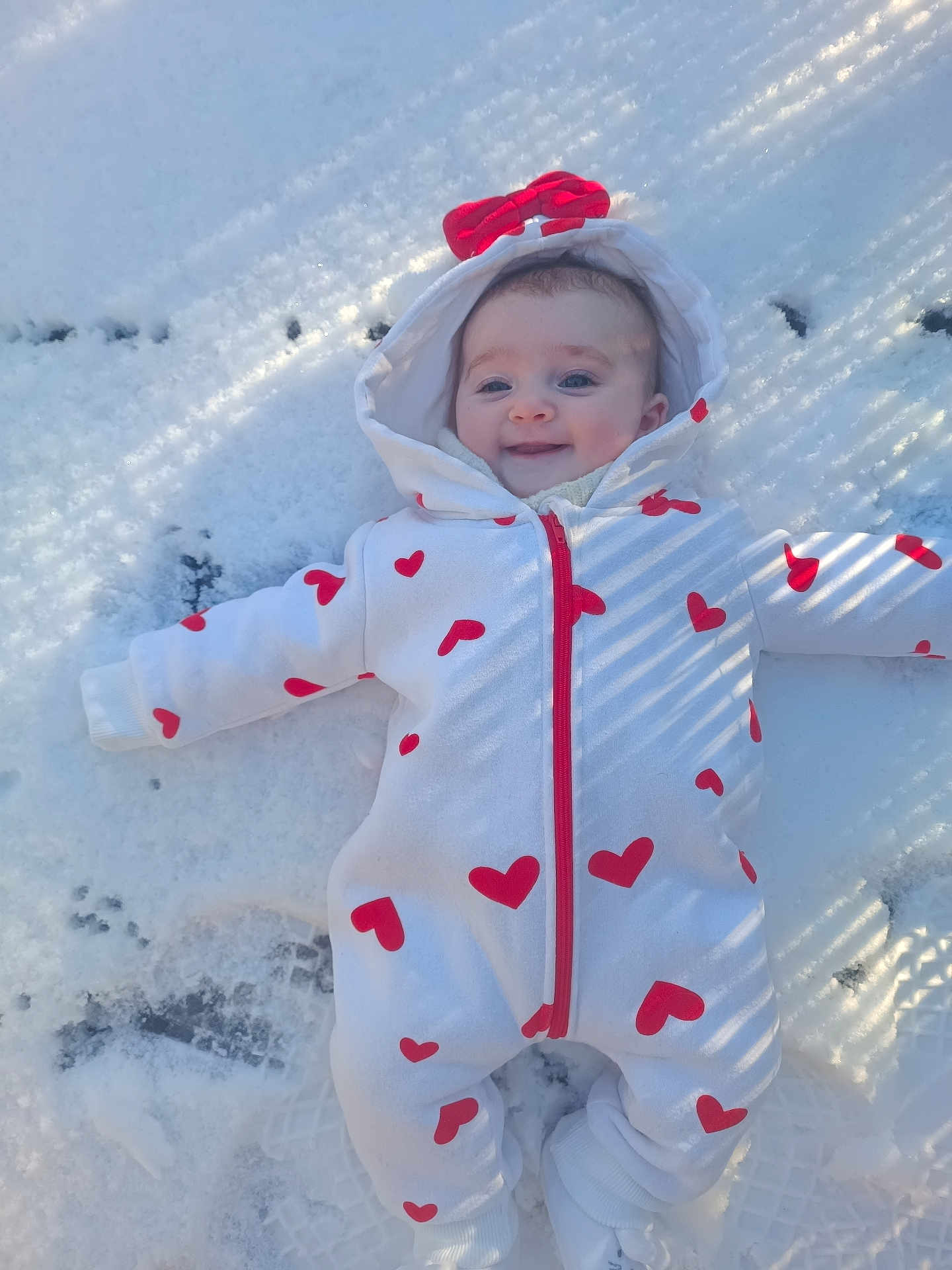 Amélia a rejoint le concours — aidez-le/la à gagner de superbes lots ! baby, child, snow, winter, onesie, heart_pattern, hood, red_bow, smile, outdoor, cold_weather, footwear, happy, face, infant, clothing, snowy_ground, cute, person, warm_clothes