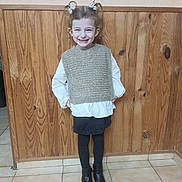 Ilyana a rejoint le concours — aidez-le/la à gagner de superbes lots ! child, girl, smiling, pigtails, vest, blouse, skirt, tights, boots, wooden_wall, tile_floor, standing, happy, indoor, portrait, cute, fashion, hands_on_hips, young, casual