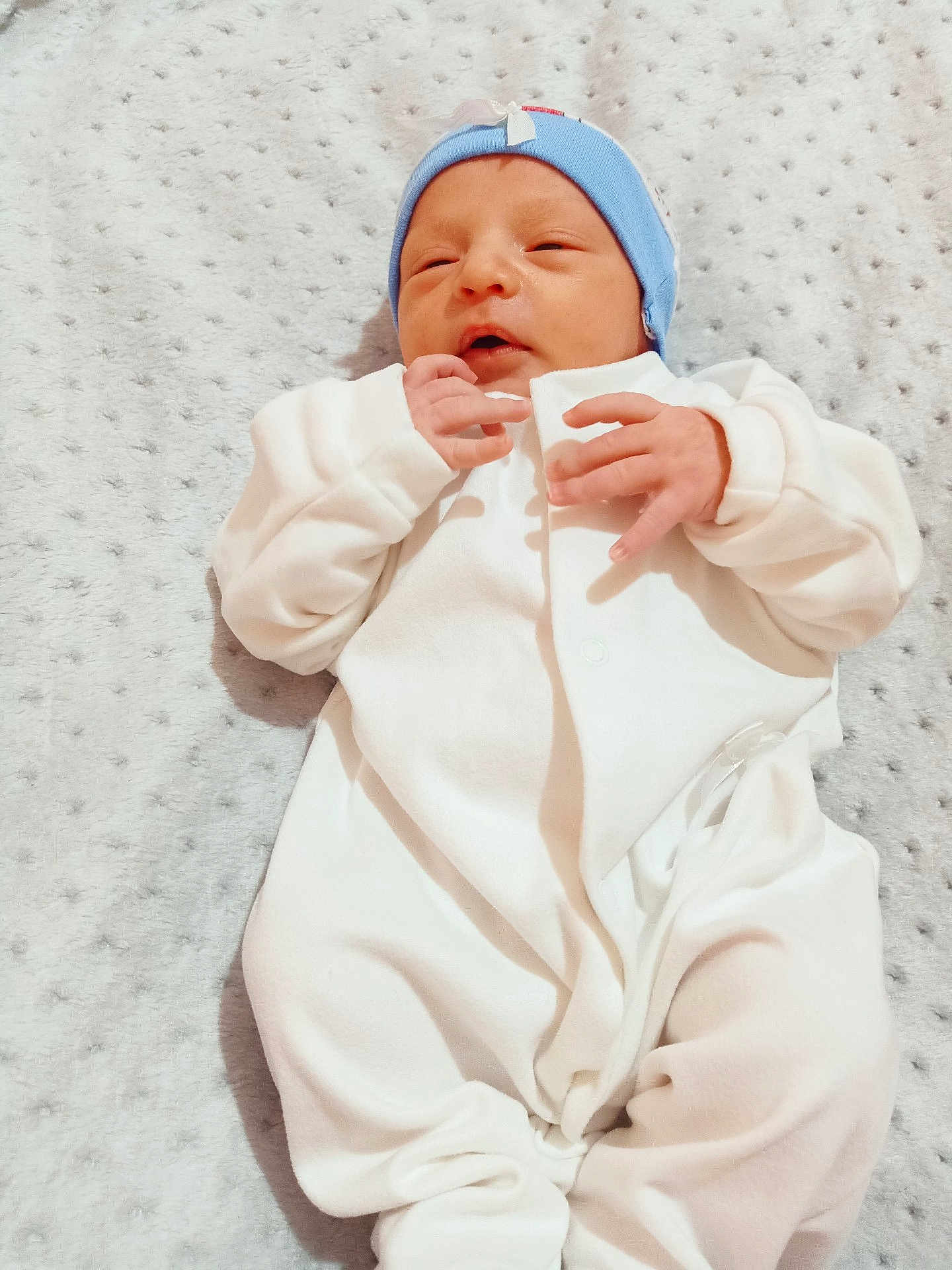 Assrar a rejoint le concours — aidez-le/la à gagner de superbes lots ! newborn, baby, infant, white_onesie, blue_hat, blanket, sleeping, soft_texture, closeup, cute, peaceful, small_hands, lying_down, indoors, portrait, baby_clothing, child, resting, cozy, infant_baby