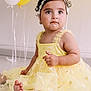 Elif a rejoint le concours — aidez-le/la à gagner de superbes lots ! toddler, child, yellow_dress, daisies, headband, balloons, sitting, cute, indoor, portrait, barefoot, curly_hair, happy, celebration, floor, baby, pretty, bright, innocent, smiling
