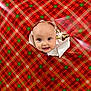 Rayah is registered to the contest to win money with this photo: baby, face, child, wrapping_paper, holiday, christmas, festive, peek, curious, smile, blue_eyes, tear, background, blur, indoor, cute, infant, head, expression, celebration