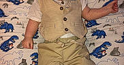 Preston Kjeldgard joined the competition — help win amazing prizes! baby, child, infant, portrait, lying_down, dinosaur_blanket, patterned_blanket, formal_clothing, vest, shirt, trousers, sock, indoors, close_up, face, looking_at_camera, serious_expression, seated_pose, textile, photography