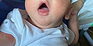 Bentley is registered to the contest to win money with this photo: baby, infant, closeup, white_clothing, expression, mouth_open, skin, face, person, young_child, indoor, onesie, head, hand, blue_eyes, newborn, human, child, portrait, casual
