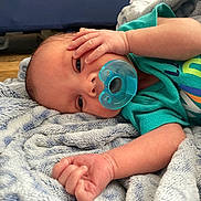 Bentley joined the competition — help win amazing prizes! baby, pacifier, blanket, infant, sleepy, hand, face, clothing, blue, soft, cute, lying_down, newborn, skin, eyes, expression, indoors, comfort, rest, child