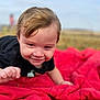 child, toddler, smiling, crawling, red_blanket, outdoor, grass, field, black_shirt, face, happy, baby, nature, young_child, head, person, cute, daytime, portrait, blond_hair