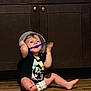 toddler, child, indoor, floor, cabinet, black_shirt, diaper, playing, hat, bowl, blue_object, barefoot, wooden_floor, fun, laughing, baby, person, cute, smiling, home