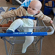 Wyatt joined the competition — help win amazing prizes! baby, shopping_cart, jacket, striped_onesie, blue_socks, store, shopping_bag, boxes, floor, curious_expression, child, indoor, retail, person, clothing, seat_belt, toy, casual, toddler, cart_handle