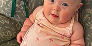 Brooklynne is registered to the contest to win money with this photo: baby, infant, sunglasses, pink_clothing, flamingo_pattern, cushion, chair, indoor, cute, chubby, smiling, face, headwear, person, skin, arm, hand, leg, comfort, relaxing